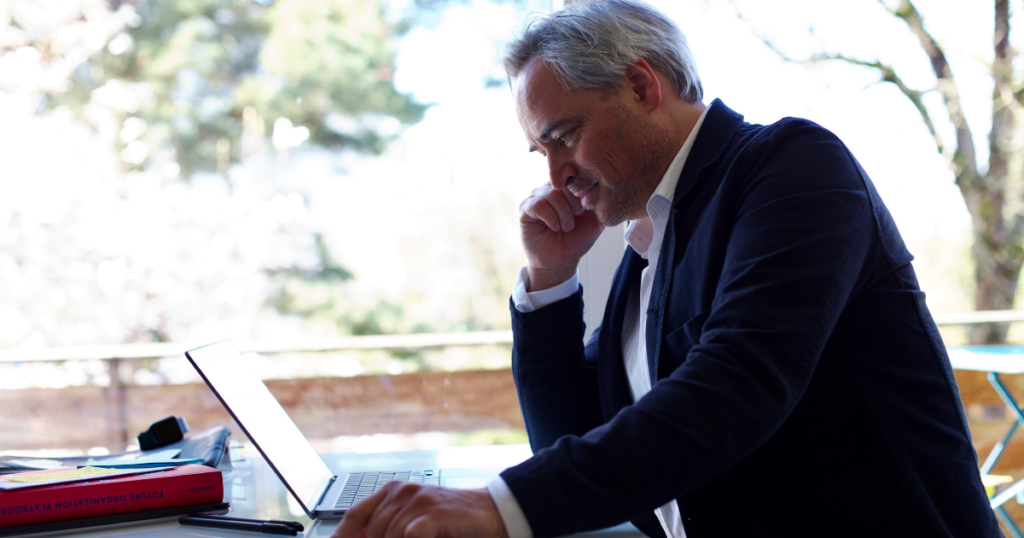 Christoph Dill von Lumanaa arbeitet an einem Laptop an einem Tisch im Freien.