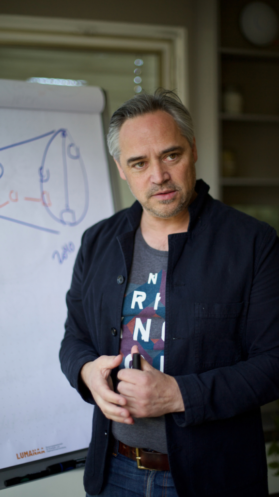 Christoph Dill von Lumanaa spricht vor einem Flipchart und gestikuliert mit einem Stift in der Hand.